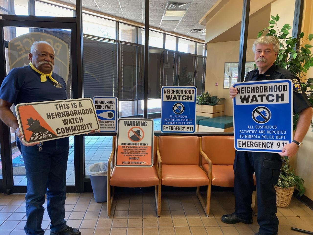 James Lee, left, and Mineola Chief of Police Chuck Bittner show some of the new neighborhood crime watch signs that were purchased with funds that Lee worked for two years to retrieve from the state’s unclaimed property held by the comptroller’s office (Courtesy photo)
